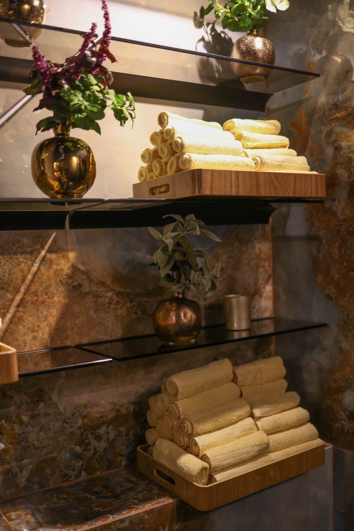Elegant spa interior with stacked rolled towels, plants, and warm lighting.