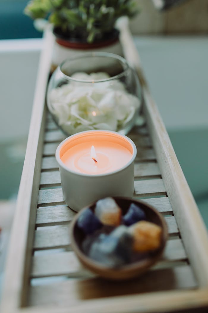 Peaceful spa setup with lit candle and healing crystals on a wooden tray.